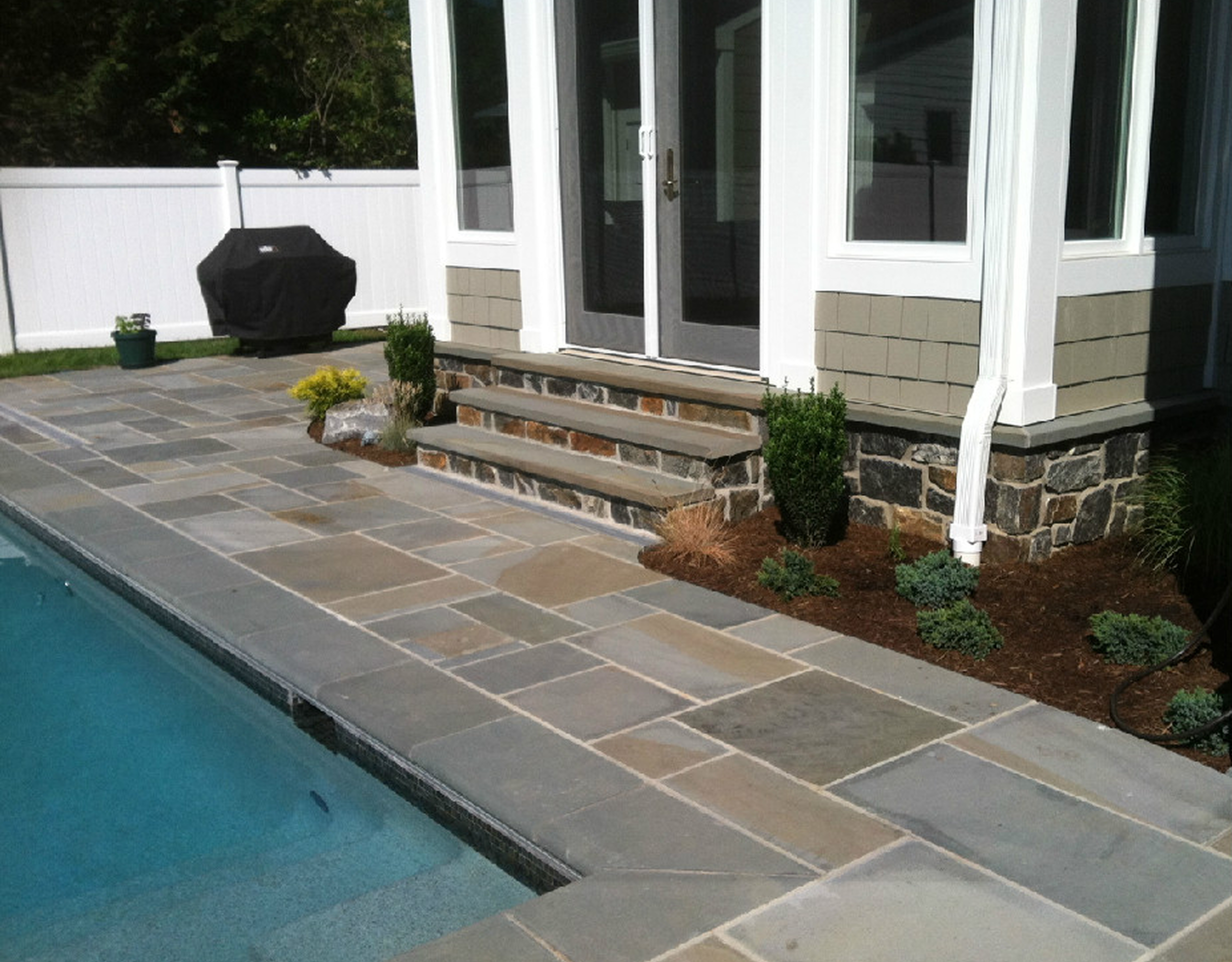 Stone patio leading to backyard pool