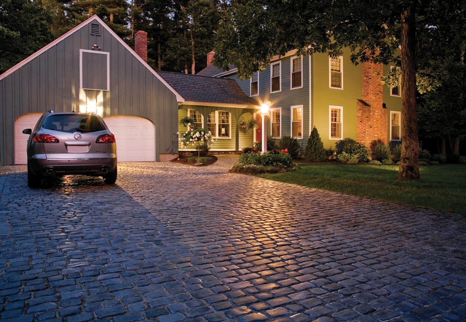 Illuminated house with cobblestone path at night