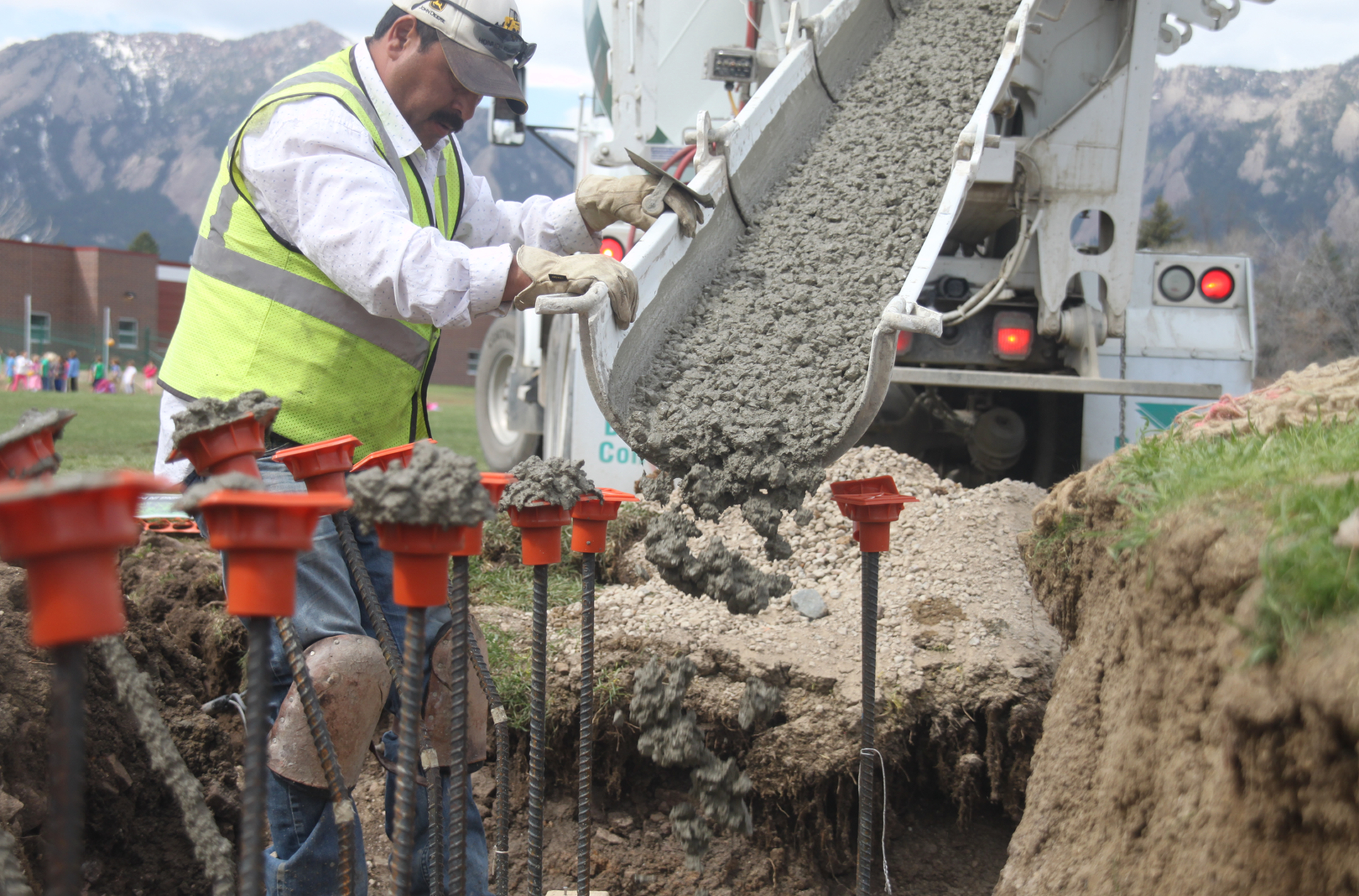 Worker directing concrete into building site trench