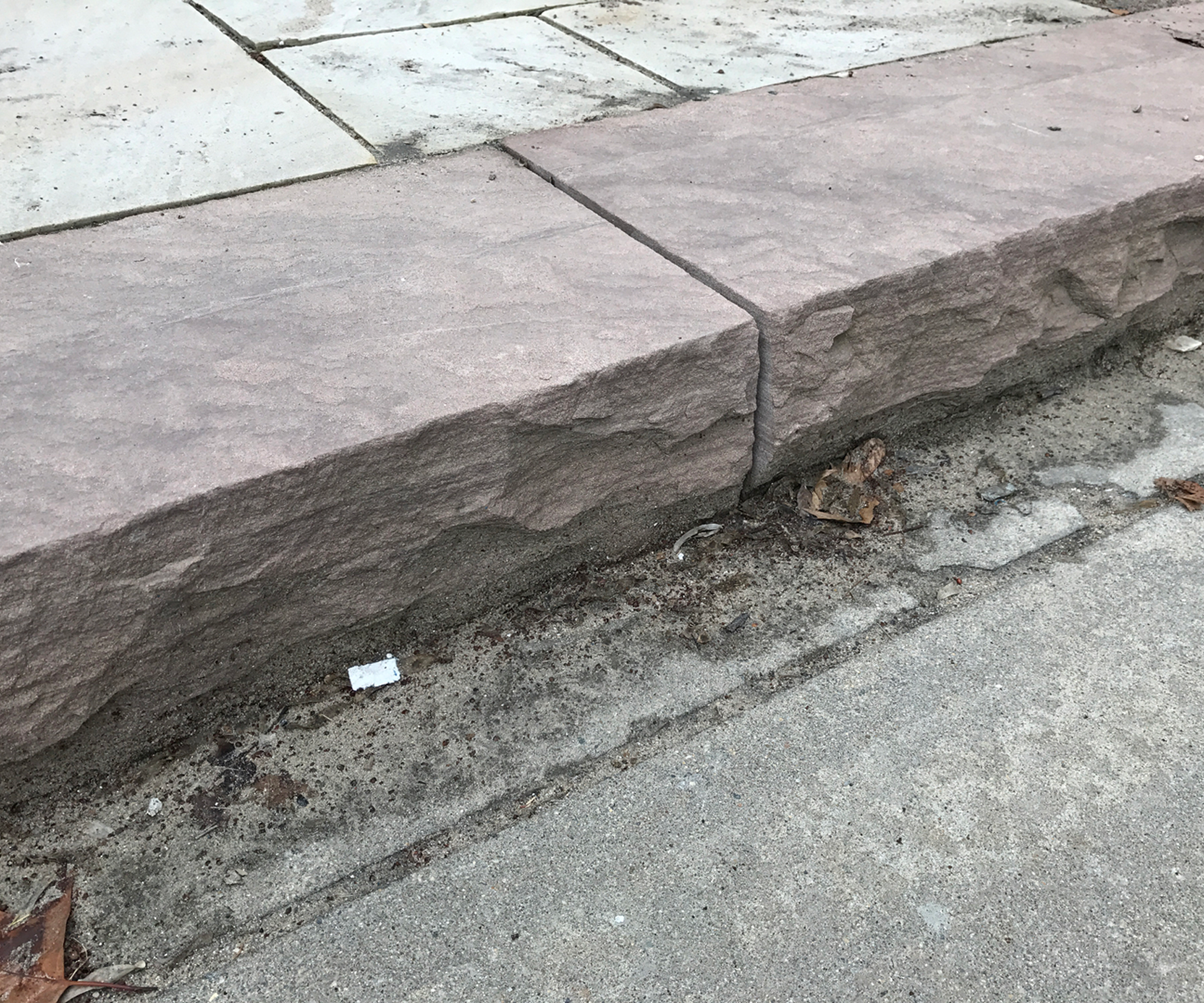 Eroded curb alongside paved sidewalk