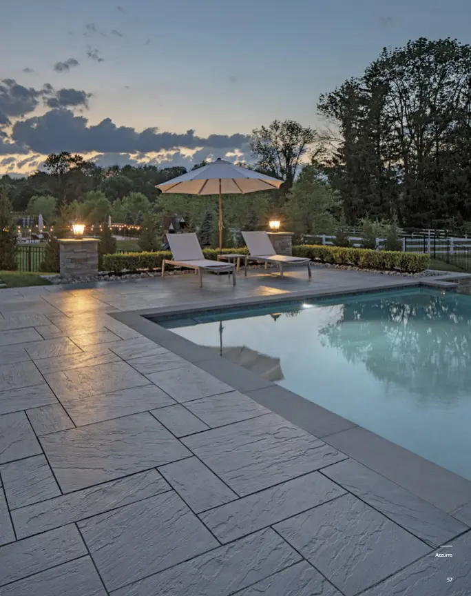 Poolside lounge chairs and umbrella at dusk